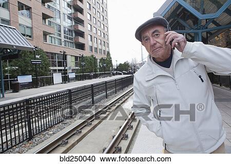 Hispanic man waiting at train station talking on cell phone View Large Photo Image Stock Image - Hispanic man waiting at train station talking on cell phone. Fotosearch