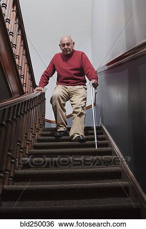 Stock Photograph - Hispanic man with cane descending staircase. Fotosearch