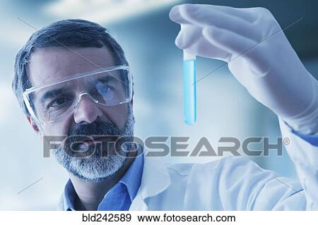 Stock Photo - Hispanic researcher holding vial of blue liquid. Fotosearch