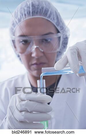 Stock Image - Hispanic scientist pouring liquid into test tube. Fotosearch