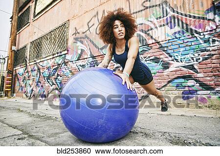 Hispanic woman balancing on fitness ball near graffiti wall View Large Photo Image Stock Image - Hispanic woman balancing on fitness ball near graffiti wall. Fotosearch