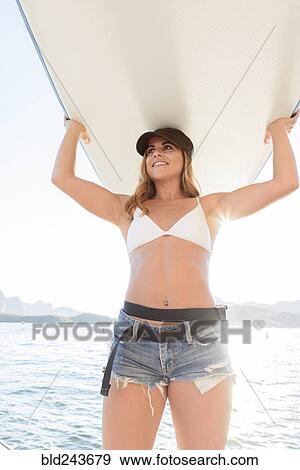 Hispanic woman carrying paddleboard near river View Large Photo Image Stock Photo - Hispanic woman carrying paddleboard near river. Fotosearch