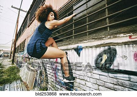 Hispanic woman climbing on bar on graffiti wall View Large Photo Image Stock Photo - Hispanic woman climbing on bar on graffiti wall. Fotosearch