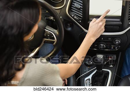 Hispanic woman driving car and pressing touch screen View Large Photo Image Picture - Hispanic woman driving car and pressing touch screen. Fotosearch