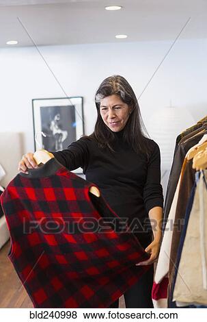 Hispanic woman examining plaid vest in store View Large Photo Image Stock Photo - Hispanic woman examining plaid vest in store. Fotosearch