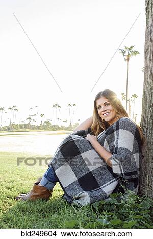 Picture - Hispanic woman leaning on tree. Fotosearch