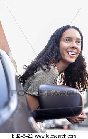Stock Image - Hispanic woman leaning out car window. Fotosearch