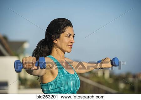 Hispanic woman lifting weights outdoors View Large Photo Image Stock Image - Hispanic woman lifting weights outdoors. Fotosearch
