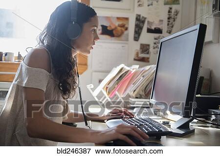 Stock Photo - Hispanic woman listening to computer with headphones. Fotosearch