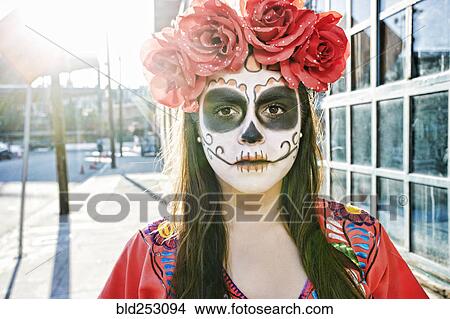 Picture - Hispanic woman on sidewalk wearing skull face paint. Fotosearch