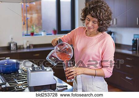 Hispanic woman pouring smoothie from blender into glassware View Large Photo Image Stock Photo - Hispanic woman pouring smoothie from blender into glassware. Fotosearch