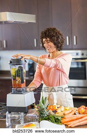 Stock Photograph - Hispanic woman preparing smoothie in blender. Fotosearch