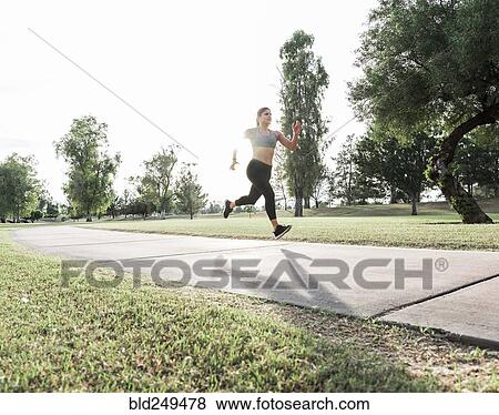 Hispanic woman running on path in park View Large Photo Image Stock Photo - Hispanic woman running on path in park. Fotosearch