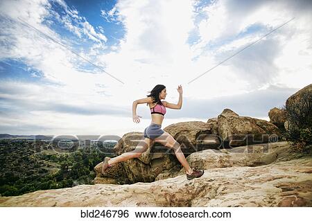 Stock Photograph - Hispanic woman running on rock formation. Fotosearch