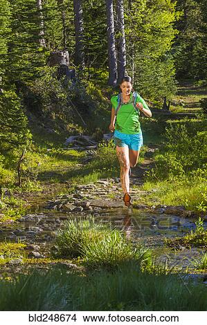 Picture - Hispanic woman running on wet trail. Fotosearch