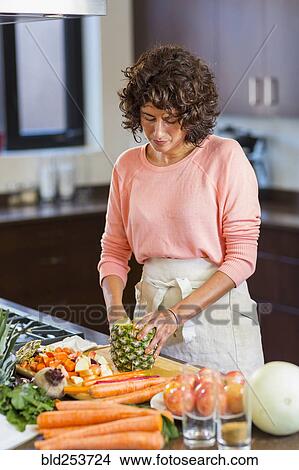 Picture - Hispanic woman slicing pineapple. Fotosearch