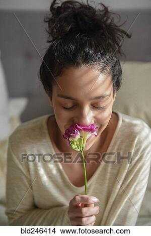 Picture - Hispanic woman smelling flower. Fotosearch