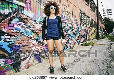 Hispanic woman standing near graffiti wall View Large Photo Image Stock Photo - Hispanic woman standing near graffiti wall. Fotosearch