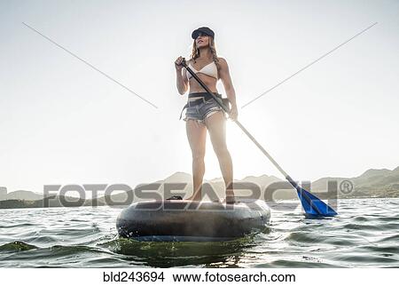 Hispanic woman standing on paddleboard in river View Large Photo Image Picture - Hispanic woman standing on paddleboard in river. Fotosearch