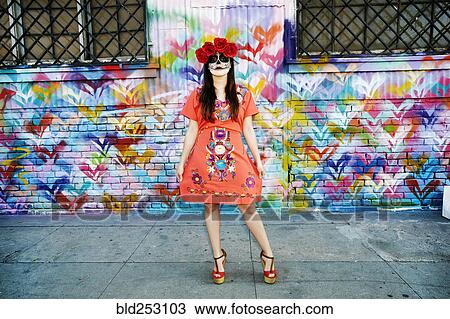 Stock Image - Hispanic woman standing on sidewalk wearing skull face paint. Fotosearch