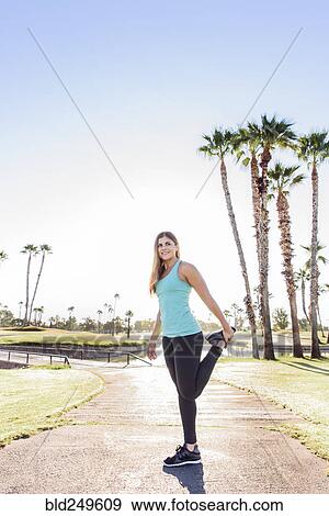 Hispanic woman stretching leg on path View Large Photo Image Stock Photo - Hispanic woman stretching leg on path. Fotosearch