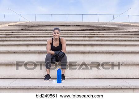 Hispanic woman wearing boxing gloves resting on bleachers View Large Photo Image Stock Image - Hispanic woman wearing boxing gloves resting on bleachers. Fotosearch
