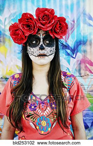 Stock Image - Hispanic woman wearing skull face paint. Fotosearch
