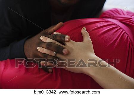 Stock Image - Husband holding pregnant wife's hand. Fotosearch