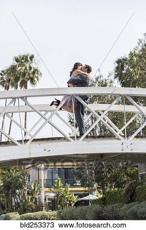 Stock Image - Kissing couple celebrating on bridge. Fotosearch