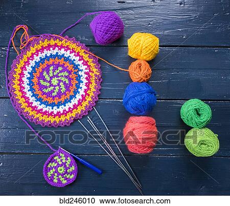 Stock Image - Knitting needles and multicolor yarn on blue table. Fotosearch