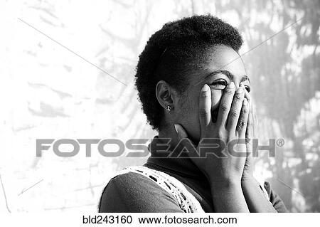 Stock Image - Laughing African American woman with hands on face. Fotosearch
