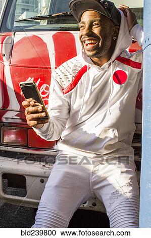 Stock Image - Laughing Black man posing for cell phone selfie. Fotosearch