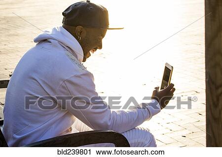 Stock Image - Laughing Black man texting on cell phone. Fotosearch