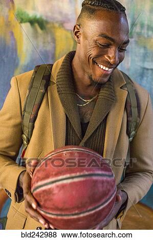 Laughing Black man wearing backpack holding basketball View Large Photo Image Stock Photo - Laughing Black man wearing backpack holding basketball. Fotosearch