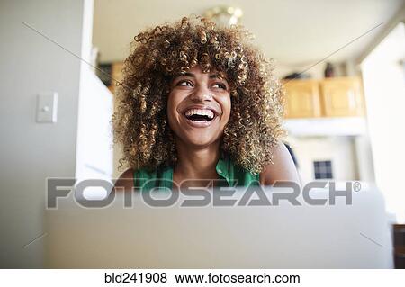 Laughing Black woman using laptop View Large Photo Image Stock Photo - Laughing Black woman using laptop. Fotosearch