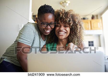 Laughing Black women hugging and using laptop View Large Photo Image Stock Photo - Laughing Black women hugging and using laptop. Fotosearch