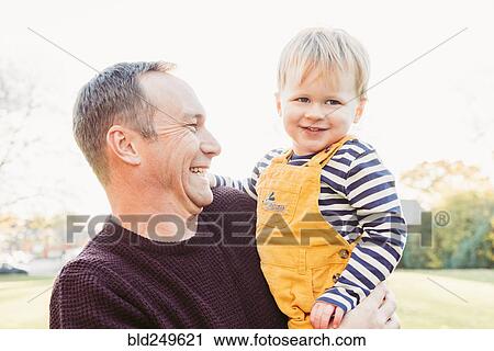 Stock Image - Laughing Caucasian father holding son. Fotosearch