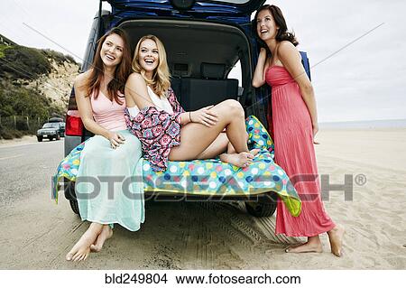 Picture - Laughing Caucasian women at hatch of car on beach. Fotosearch