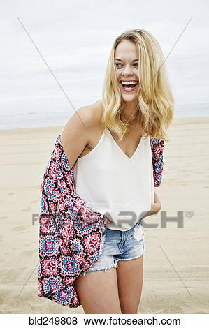 Stock Photo - Laughing Caucasian women standing on beach. Fotosearch