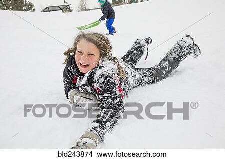 Laughing girl laying in snow in winter View Large Photo Image Picture - Laughing girl laying in snow in winter. Fotosearch