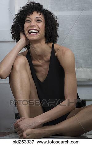 Laughing Mixed Race woman sitting on counter View Large Photo Image Stock Photo - Laughing Mixed Race woman sitting on counter. Fotosearch