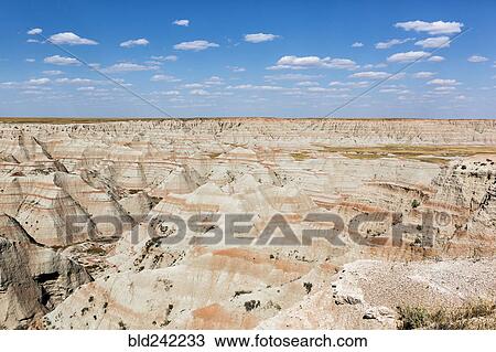 Stock Image - Layered rock formations under blue sky, Badlands National Park, South Dakota, United States. Fotosearch