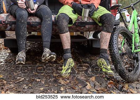 Stock Photography - Legs of Caucasian couple sitting in pickup truck near bicycle. Fotosearch