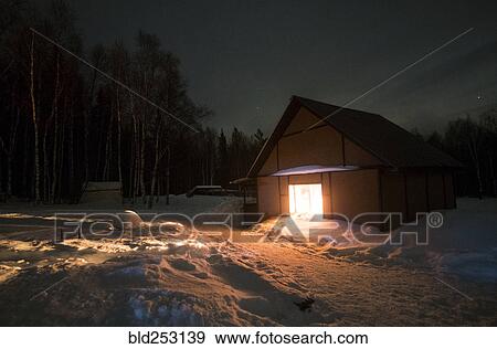 Stock Photo - Light glowing in remote barn in winter. Fotosearch