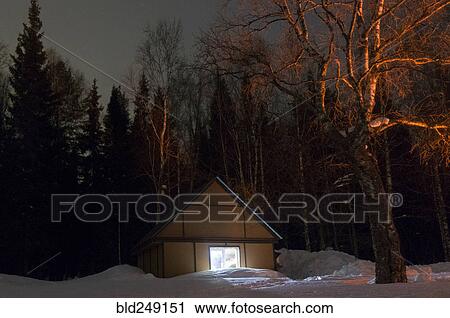 Stock Image - Light glowing in remote cabin in winter. Fotosearch