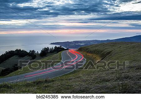 Stock Photography - Light trails on winding road near ocean. Fotosearch