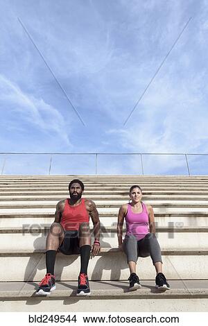 Picture - Man and woman doing triceps dips on bleachers. Fotosearch