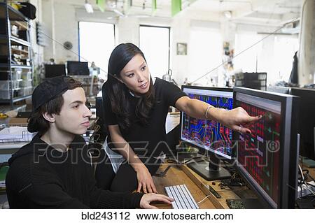 Stock Image - Man and woman examining circuits on computer monitors. Fotosearch