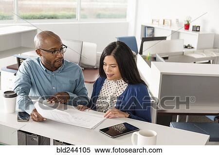 Stock Photography - Man and woman reading paperwork in office. Fotosearch