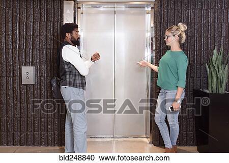 Stock Image - Man and woman waiting for elevator. Fotosearch